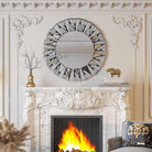 Round silver sunburst mirror with beveled mirror shards above a carved white marble fireplace