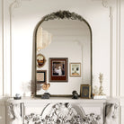 Antique silver baroque arched mirror above a carved white mantel