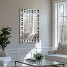 Vertical Greek-key Venetian mirrored glass wall mirror in a bright living room