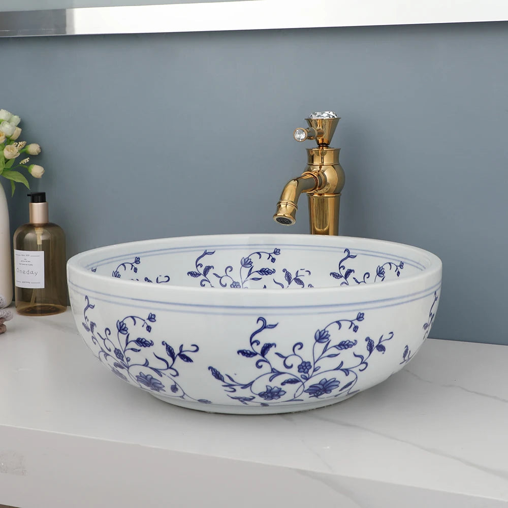 Hand-painted blue and white ceramic vessel sink and gold faucet, front view on a white counter
