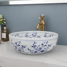 Hand-painted blue and white ceramic vessel sink and gold faucet, front view on a white counter