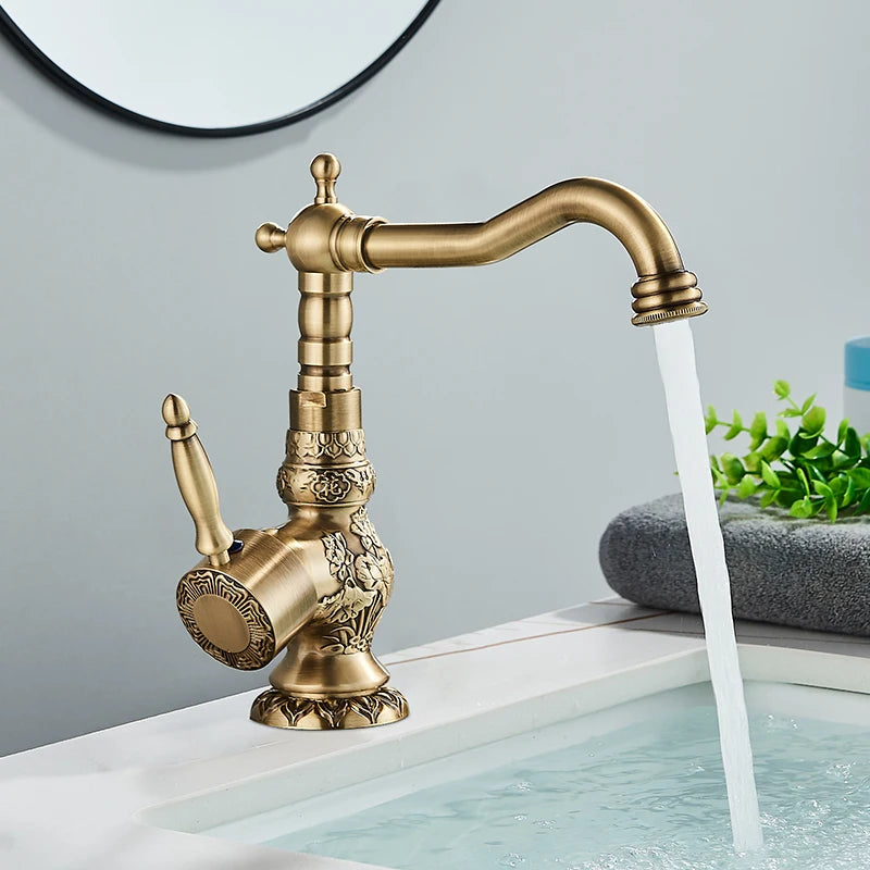 Antique brass carved single-handle faucet running water beside a round mirror and greenery