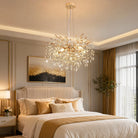 Gold crystal branch chandelier lit above a bed in a warm bedroom