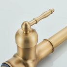 Close-up of the antique brass kitchen faucet lever handle with ornate finial and domed cap