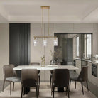 Brass three-light linear pendant with clear glass shades in a dining room