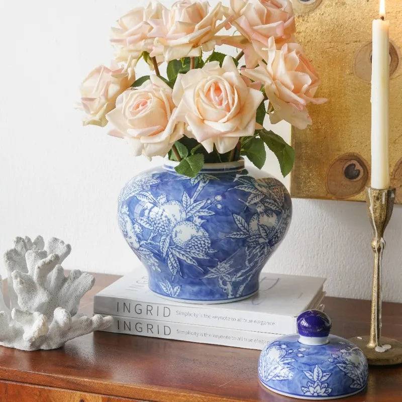 Blue and white porcelain jar used as a vase with peach roses, lid set beside it