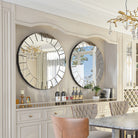 Pair of Venetian-style ornate round mirrors with beveled panels above a dining room buffet