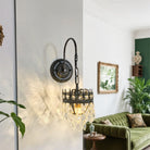 Black iron arm crystal wall sconce casting light in a living room with green sofa