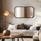Octagon walnut wood wall mirror hung horizontally above a cream sofa
