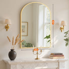 Arched gold frame vanity mirror over a marble mantel with 40 x 30 in dimensions