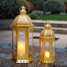 Set of two gold Moroccan candle lanterns with filigree domes and glass panels (on a patio)