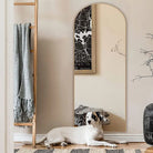 Pale wood arched floor mirror on its stand in a bright living room