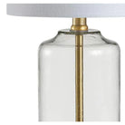 Close-up of the clear glass lamp body with brass center rod beneath the linen shade
