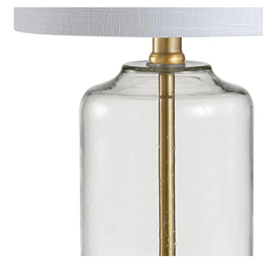 Close-up of the clear glass lamp body with brass center rod beneath the linen shade