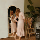 Woman checking her outfit in a tall arched rattan mirror