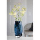 Blue-teal art glass vase with yellow flowers in a living room