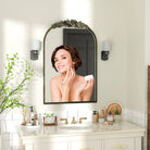 Antique brass baroque arched mantel mirror above a white bathroom vanity