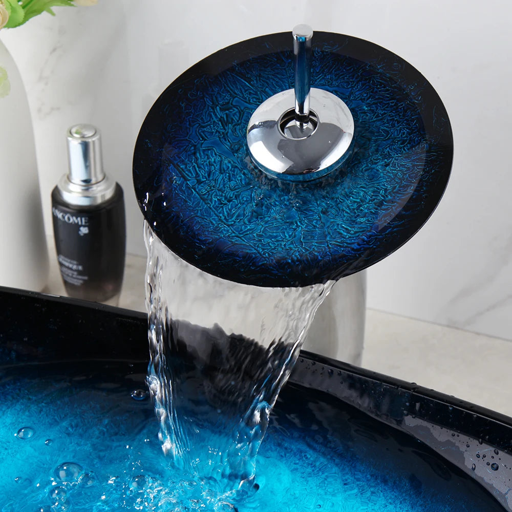 Chrome waterfall faucet with blue glass disc pouring into the blue gradient glass vessel sink