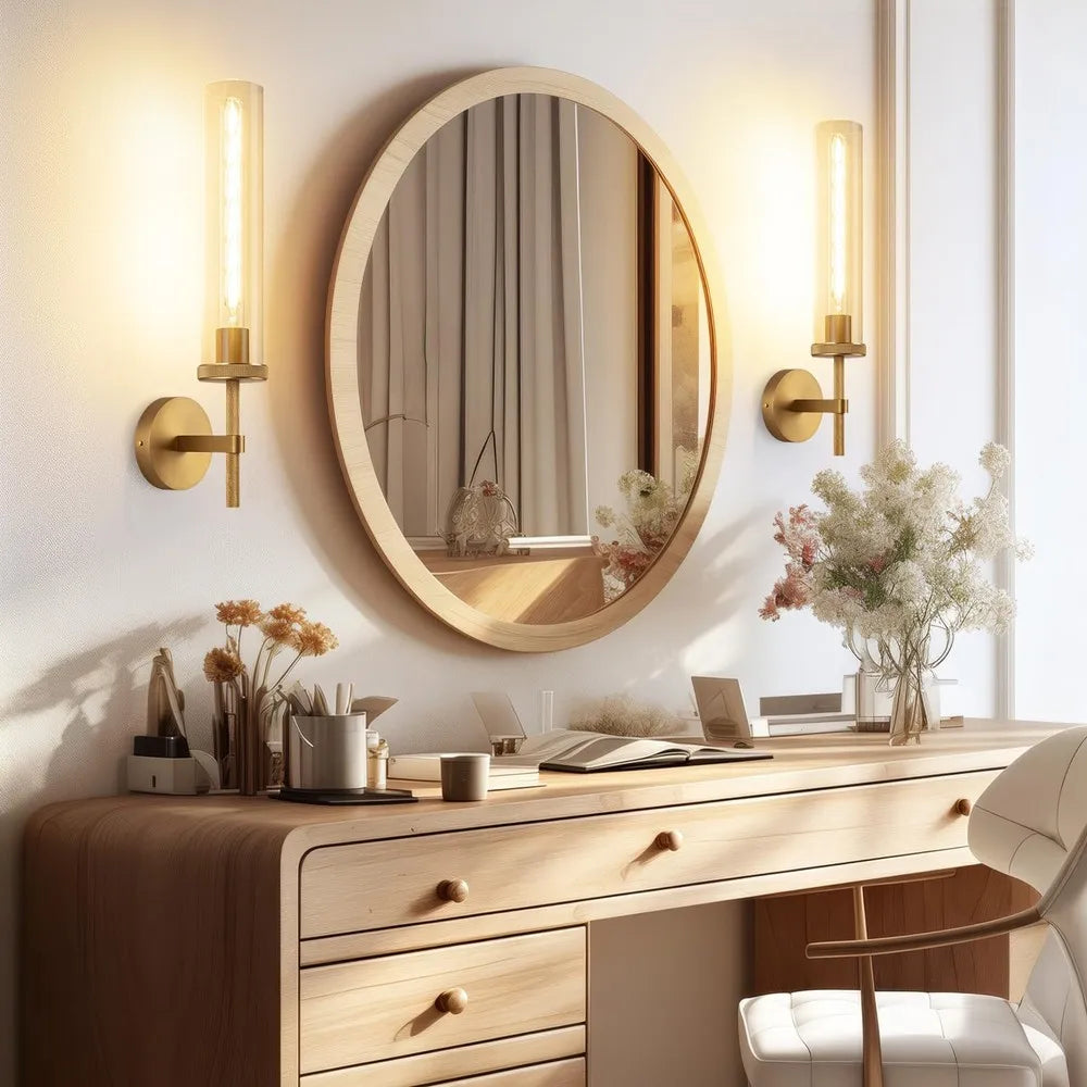 Gold glass-tube wall sconces beside a round mirror above a bathroom vanity
