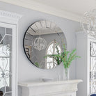 Ornate round Venetian-style mirror with mirrored panel frame above a white mantel