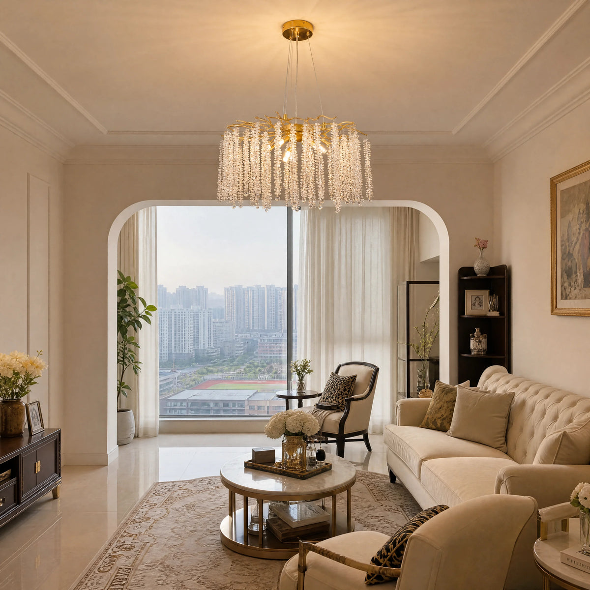 Gold branch chandelier with raindrop crystals in a living room with an arched window view