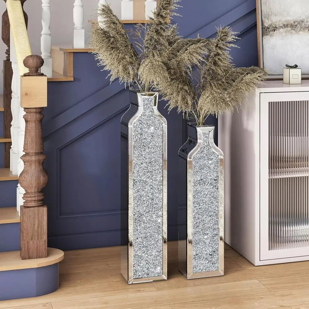 Two mirrored crushed-crystal floor vases with dried pampas grass at the foot of a staircase