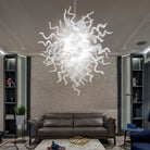 Hand-blown white glass art chandelier hanging above a living room sofa and coffee table