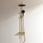 Gold 3-way exposed rainfall shower system with round rain head, handheld shower and mixer on a cream wall