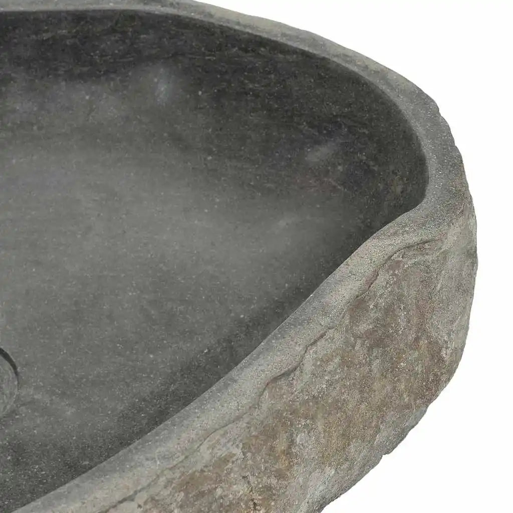 Close-up of the river-stone vessel sink rim showing smooth basin and rough natural edge