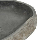 Close-up of the river-stone vessel sink rim showing smooth basin and rough natural edge