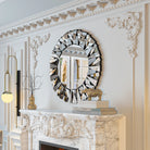 Sunburst wall mirror with faceted mirror frame hung over a white mantel