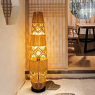 Woven rattan floor lamp beside shelves with plants