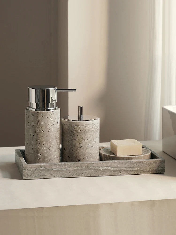 Round gray travertine soap dispenser, toothbrush holder and soap on a travertine tray