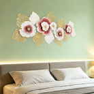 Blush pink and gold metal flower wall sculpture above a bed on a sage green wall
