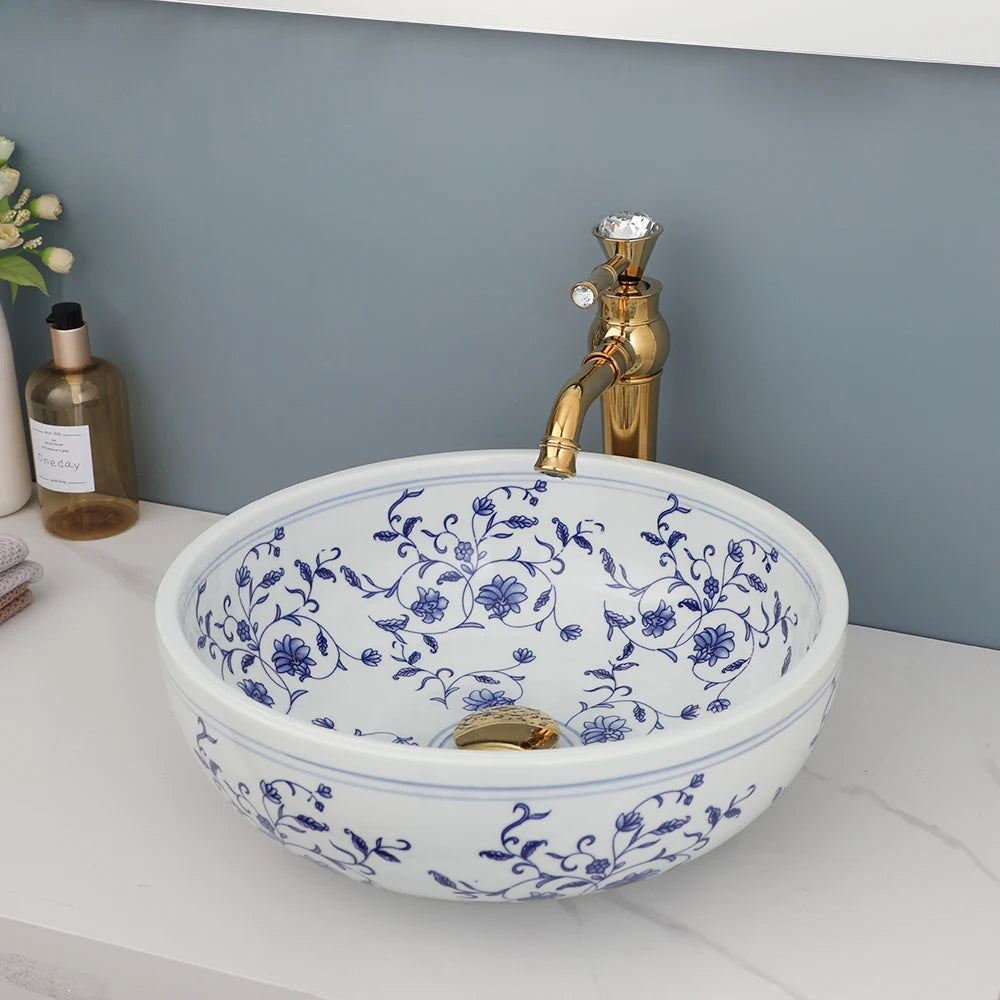 Blue and white ceramic vessel sink showing painted vines inside the bowl with gold faucet