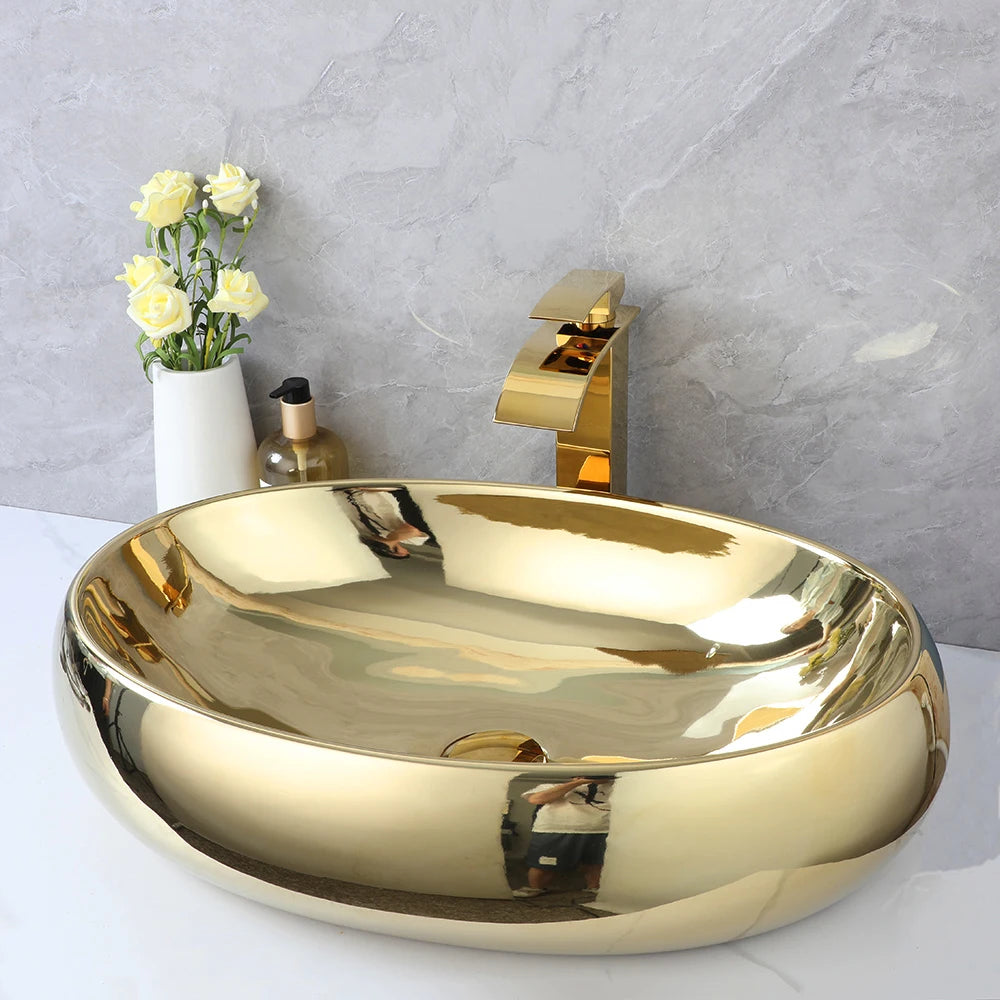 Gold ceramic oval vessel sink with gold waterfall faucet on a white counter