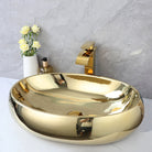 Gold ceramic oval vessel sink with gold waterfall faucet on a white counter