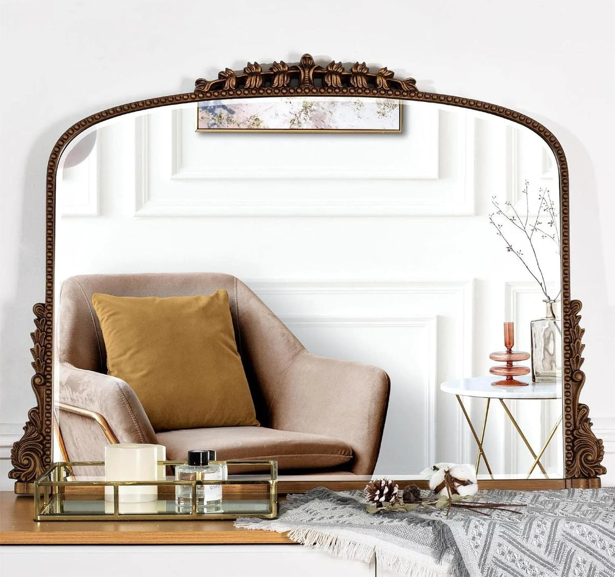 Antique gold baroque mirror with scalloped crest on a dresser reflecting an armchair