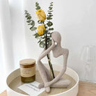 Sandstone-finish thinker sculpture on a round tray with yellow tulips and a candle