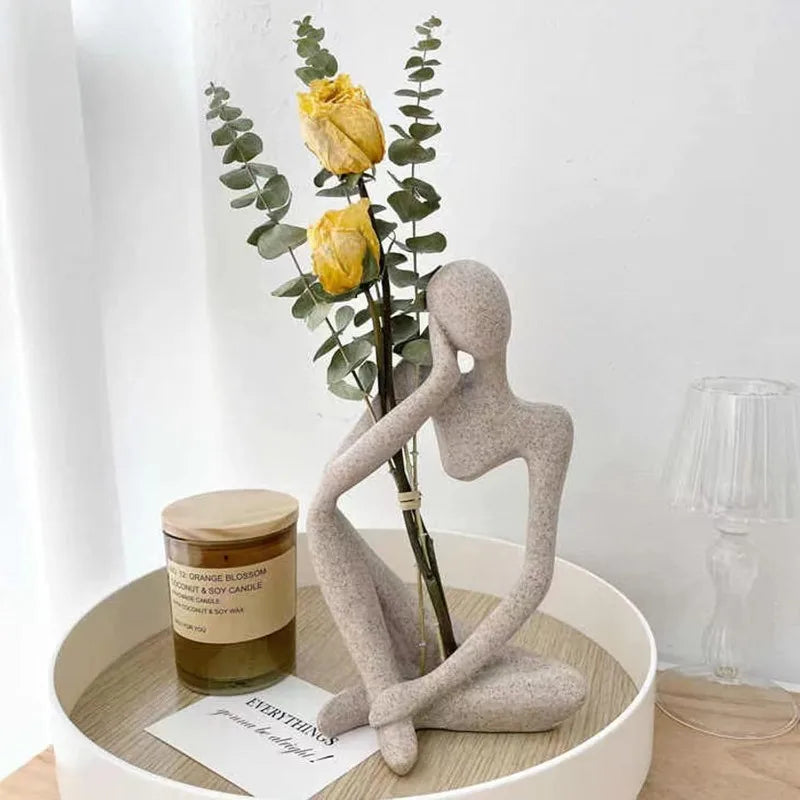 Sandstone-finish thinker sculpture on a round tray with yellow tulips and a candle