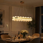 Lit oval alabaster stone chandelier with brass ring over a dining table with roses