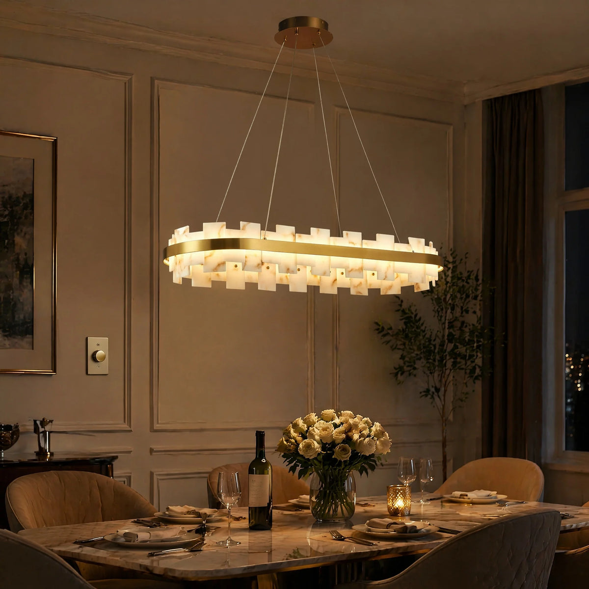 Lit oval alabaster stone chandelier with brass ring over a dining table with roses