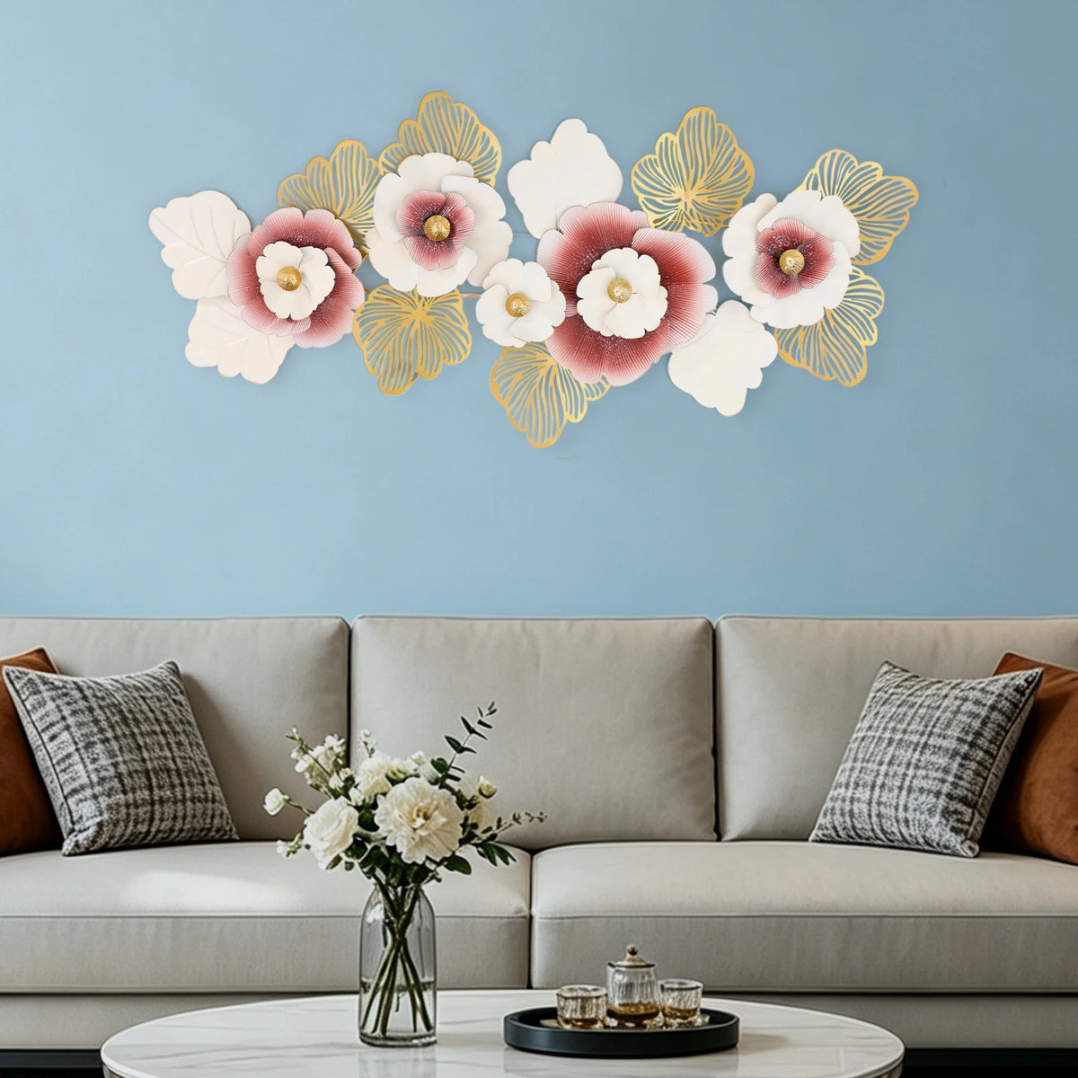 Pink and gold metal flower wall art above a sofa on a soft blue wall