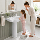 White pedestal sink with a step stool in a family bathroom