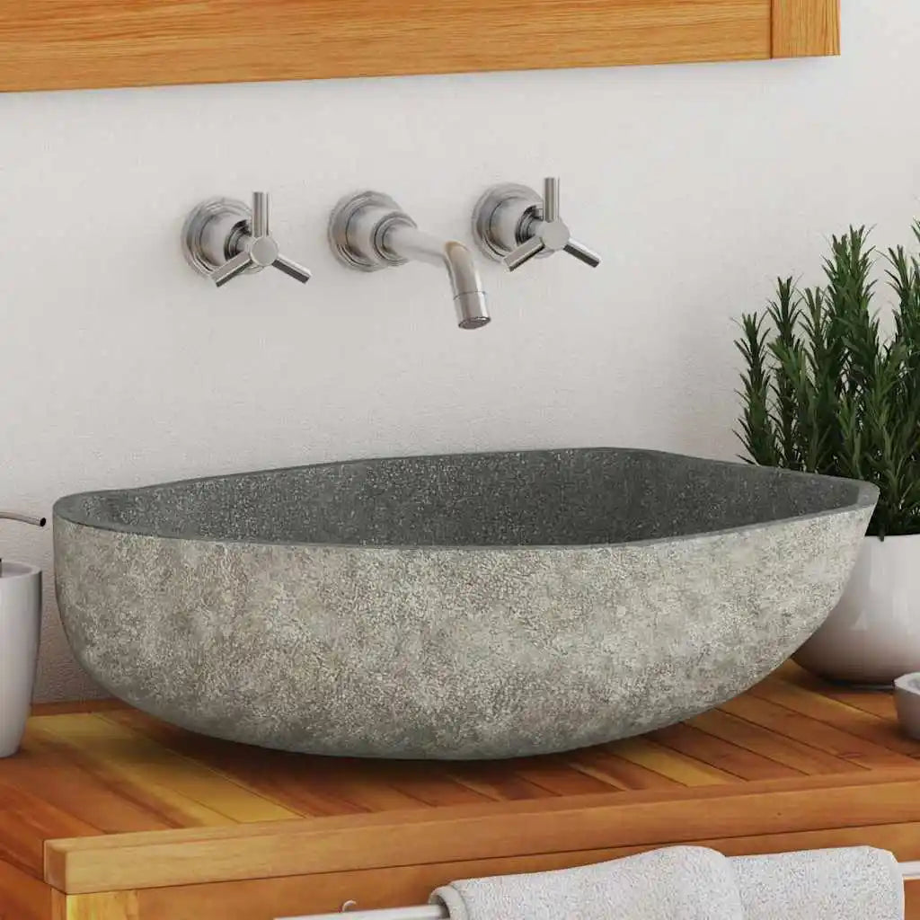 Natural river-stone oval vessel sink on a teak vanity below a wall-mount faucet