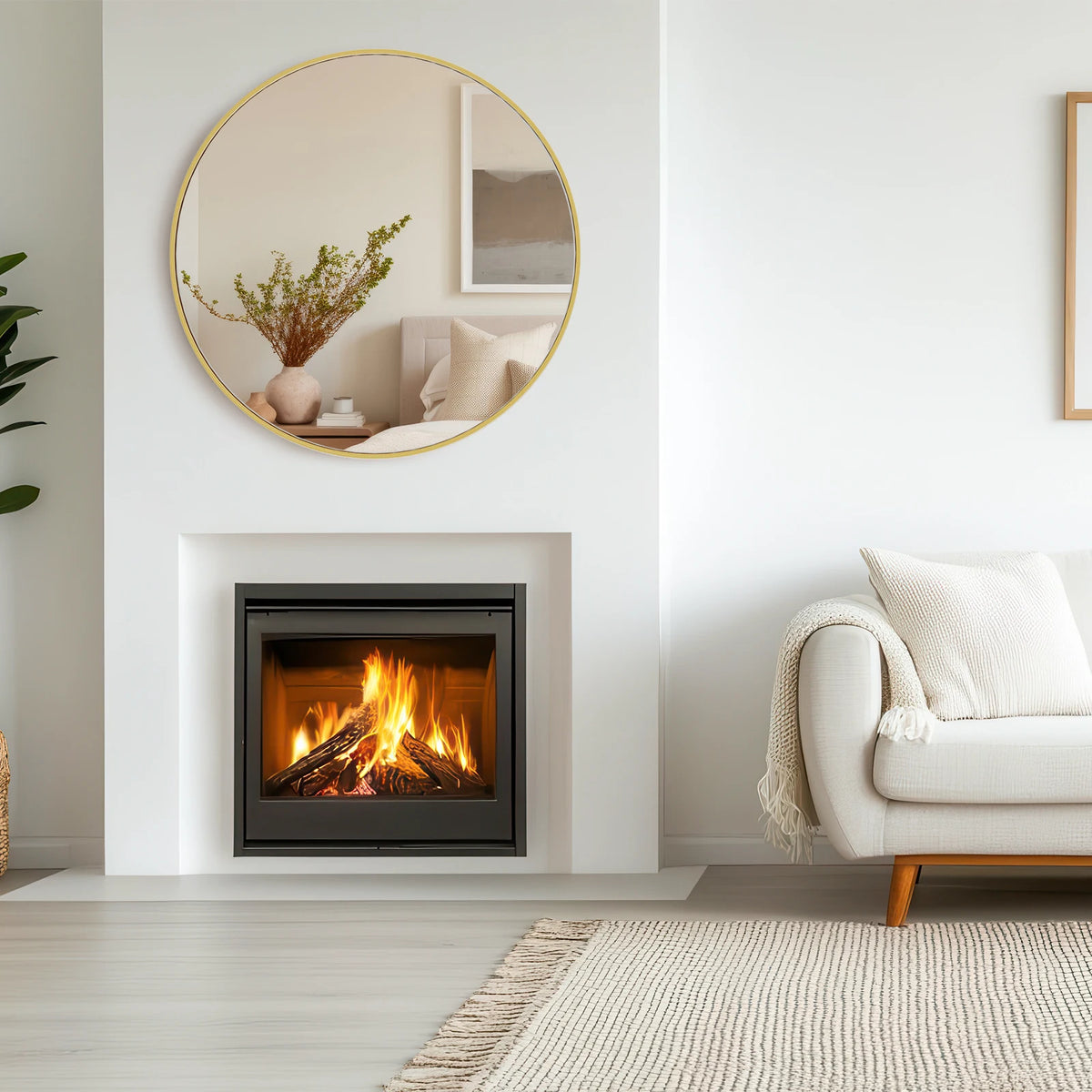 Round matte gold metal frame mirror hung above a modern fireplace in a living room