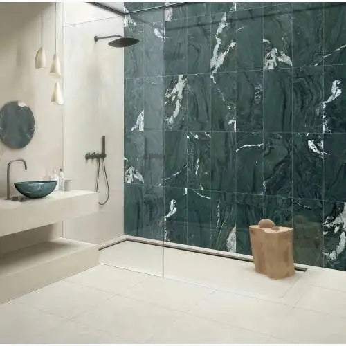 Green natural marble vessel sink in a bathroom with matching green marble shower wall