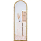 Rattan arched full-length mirror, 64 x 20 in, leaning against a wall