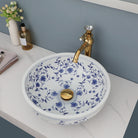Hand-painted blue and white ceramic vessel sink with gold faucet and drain, seen from above