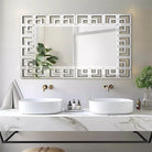Greek-key Venetian mirror above a white marble double vanity with vessel sinks
